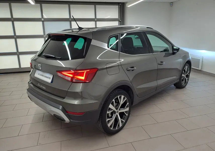 Vue 3/4 arrière droite du SEAT Arona gris falaise 2024 avec jantes alliage 18'' et vitres arrière surteintées.