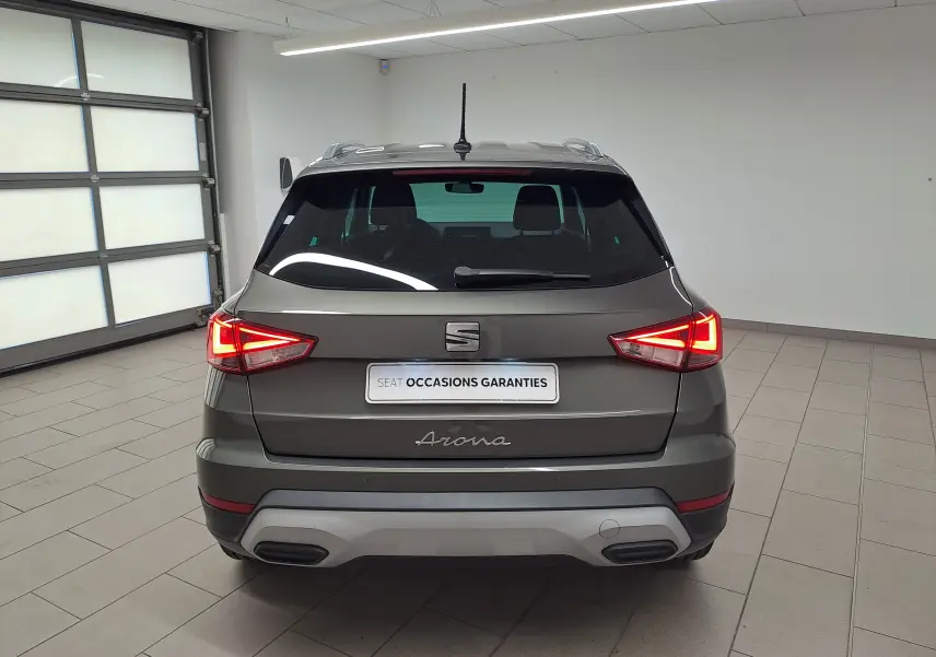 Vue arrière d'un SEAT Arona gris falaise 2024 avec feux LED allumés et bouclier arrière spécifique XPERIENCE.