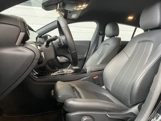 Intérieur avant droit d'une Mercedes CLA 200 d noire, sièges cuir gris, volant multifonctions et console centrale brillante.