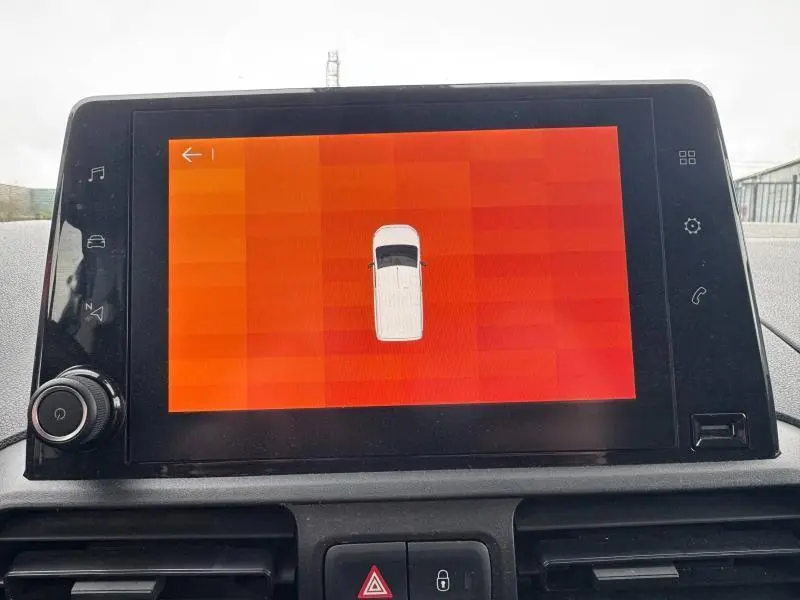Écran tactile du tableau de bord du Citroën Berlingo Fourgon blanc, affichant l'aide au stationnement en vue aérienne.