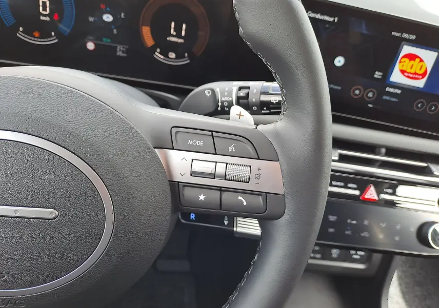 Vue rapprochée du volant noir du Hyundai Tucson 2025 avec commandes intégrées et tableau de bord numérique lumineux.