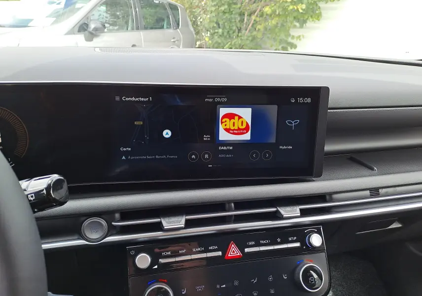 Vue intérieure du tableau de bord du Hyundai Tucson 2025, écran tactile affichant navigation et radio, finition noire moderne.