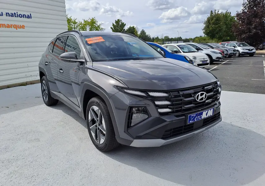 Vue 3/4 avant d'un Hyundai Tucson 2025 gris Ecotronic avec calandre distinctive et jantes alliage biton.