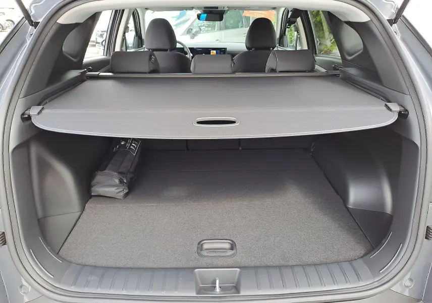 Coffre ouvert du Hyundai Tucson 2025 gris Ecotronic, vue arrière montrant la plage arrière et l'habitacle noir.