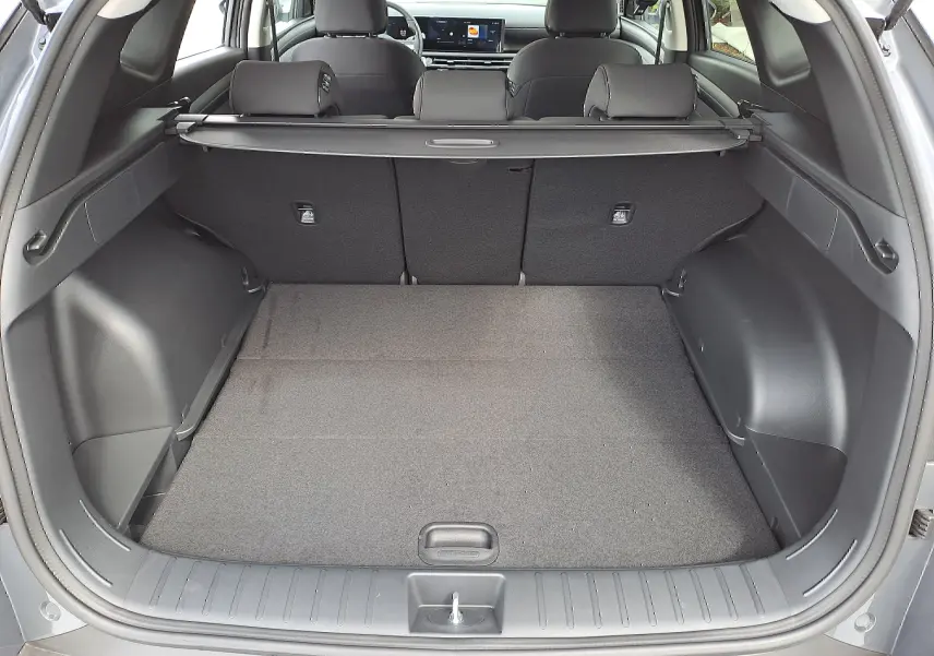 Coffre ouvert du Hyundai Tucson 2025 gris Ecotronic, vue arrière montrant l'espace de chargement et la banquette arrière noire.