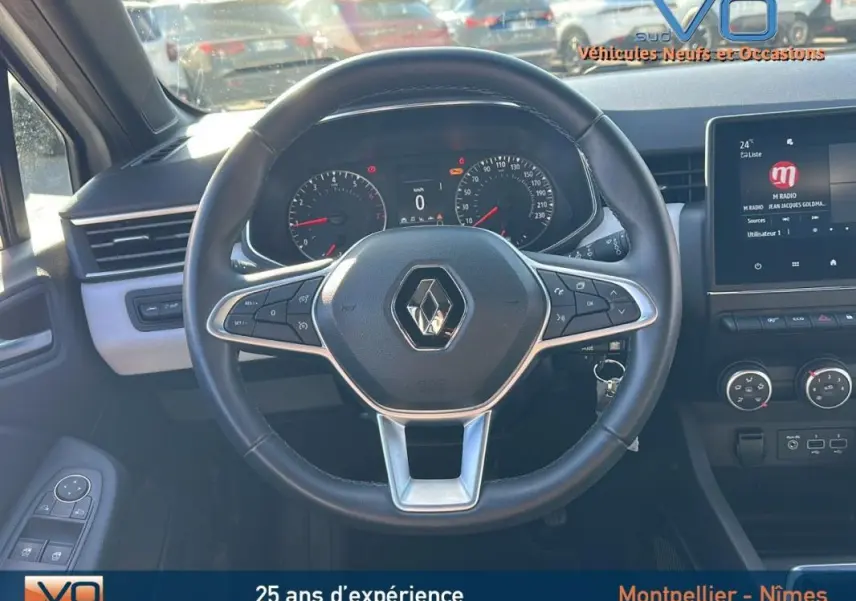 Vue intérieure centrée sur le volant de la Renault Clio blanc 2021 avec tableau de bord et écran tactile visible.