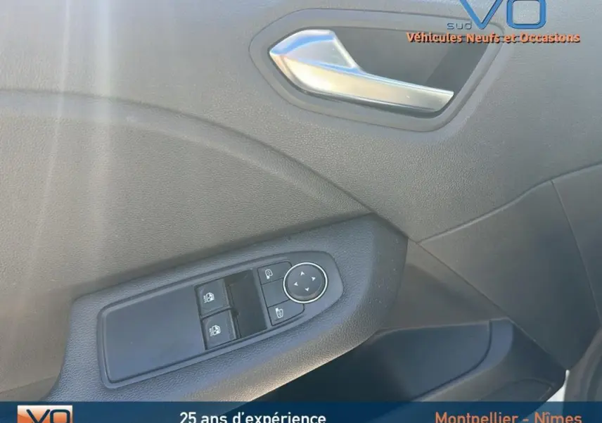 Détail de la porte avant gauche de la Renault Clio blanc, avec commandes des vitres et poignée intérieure argentée.