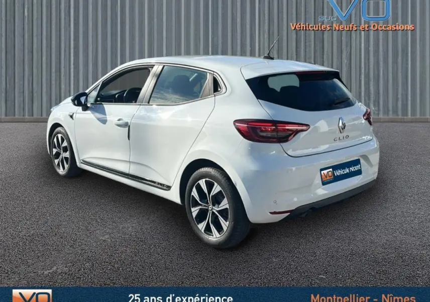 Vue 3/4 arrière gauche d'une Renault Clio blanche 2021 avec jantes alliage 16 pouces et vitres teintées.