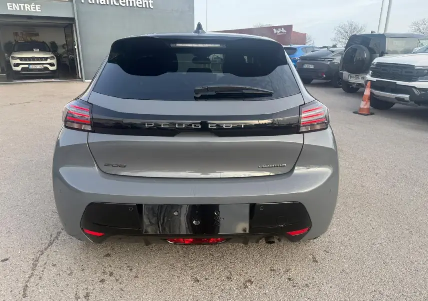 Vue arrière d'une Peugeot 208 Hybrid gris 2025 avec feux LED et jantes alliage visibles en extérieur.