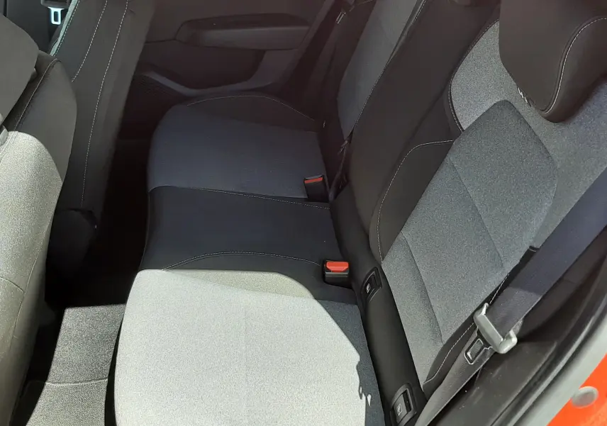 Vue intérieure côté arrière droit montrant la banquette tissu gris et noir d'une Renault Clio V rouge flamme 2024.