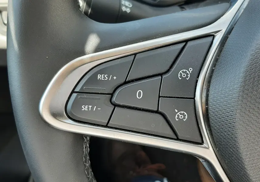 Gros plan sur les commandes de régulateur de vitesse au volant d’une Renault Clio V, intérieur noir.
