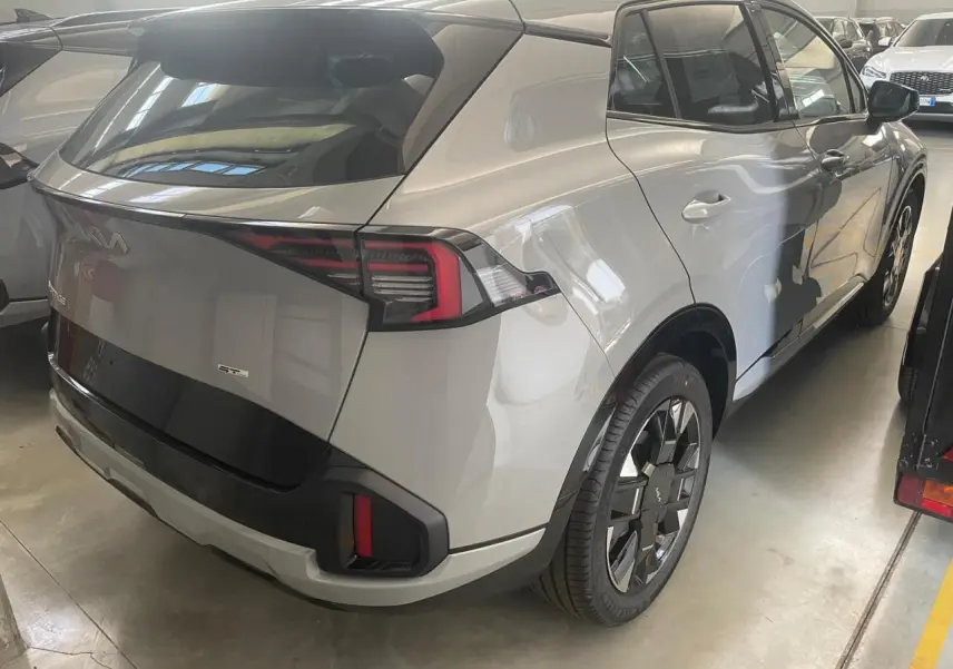 Vue 3/4 arrière droite du KIA SPORTAGE 2026 hybride gris loup avec jantes noires et feux arrière LED distinctifs.