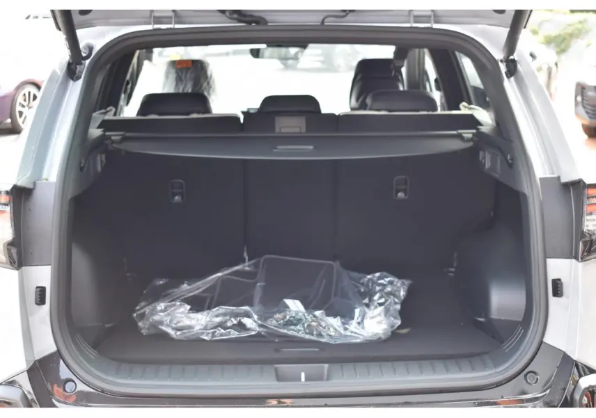Coffre ouvert d’un KIA Sportage hybride gris, vue arrière montrant l’espace de chargement vide avec cache-bagages déployé.