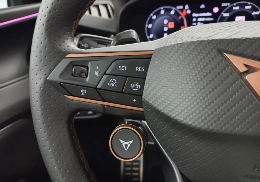 Gros plan sur le volant perforé de la CUPRA TERRAMAR 2025 avec commandes multifonctions et insert cuivré distinctif.
