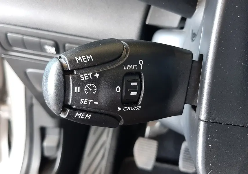 Gros plan sur la commande de régulateur de vitesse à gauche du volant dans un Citroën C3 Aircross 2021 sable métal.