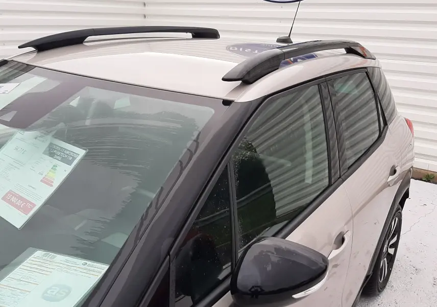 Vue 3/4 avant droit du Citroën C3 Aircross sable métal avec barres de toit noires et vitres teintées.