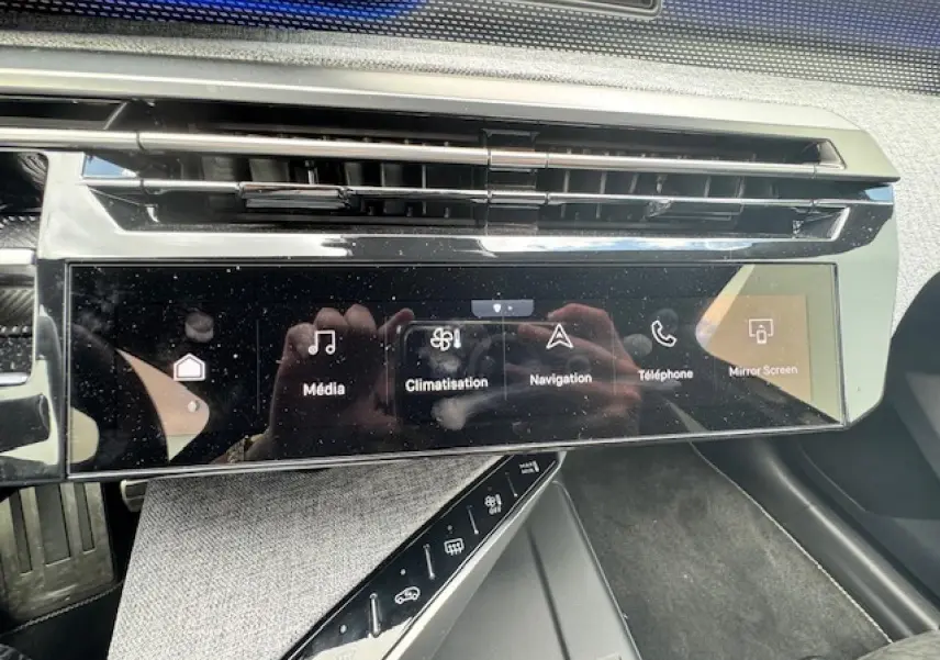 Écran tactile central du tableau de bord du Peugeot 5008 gris titane, avec commandes multimédia et climatisation visibles.