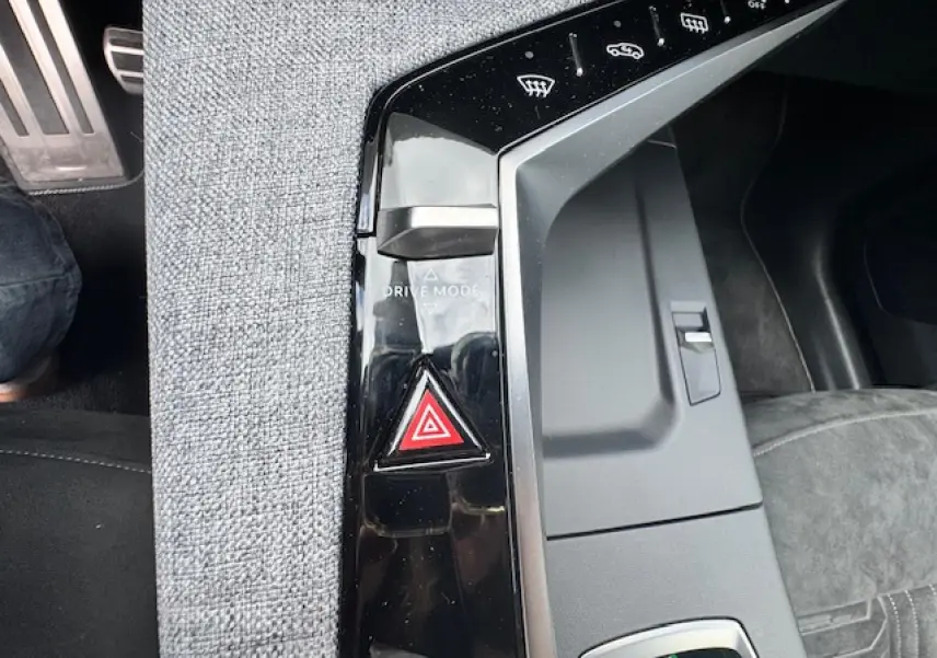 Gros plan sur la console centrale noire brillante avec bouton de mode de conduite et signal d'alarme du Peugeot 5008 gris titane.