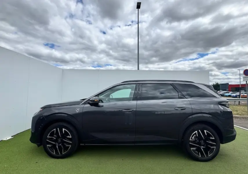 Profil côté gauche du Peugeot 5008 gris titane avec toit noir, jantes alliage 19 pouces et vitres teintées.