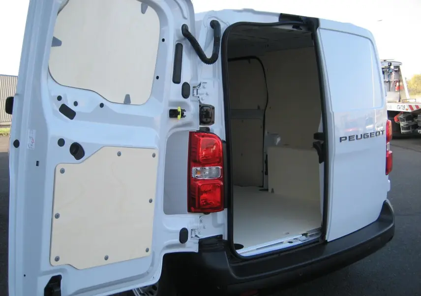 Vue arrière droite d'un Peugeot Expert Fourgon blanc 2025 avec portes ouvertes montrant l'intérieur vide et aménagement bois.