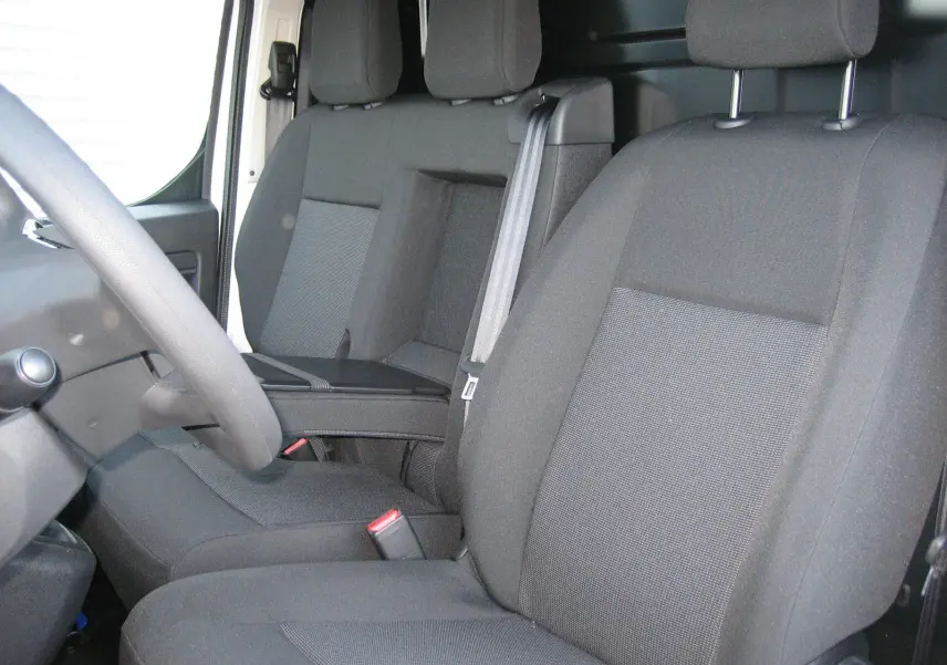 Vue intérieure du côté conducteur du Peugeot Expert Fourgon 2025, sièges tissu gris foncé avec accoudoir central.