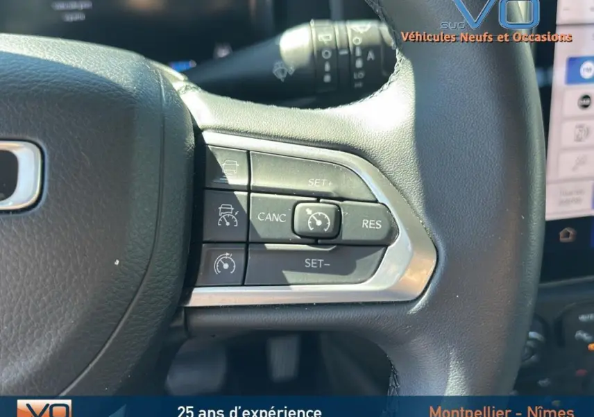 Gros plan sur les commandes du régulateur de vitesse au volant noir du Jeep Renegade 2024 e-Hybrid Summit.