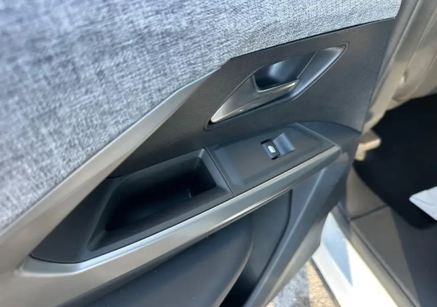 Gros plan sur la porte intérieure côté gauche du Peugeot 3008 blanc, montrant la poignée et les commandes de vitre.