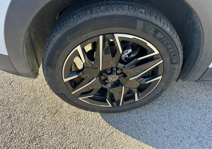 Gros plan sur la jante alliage 19 pouces noire et argentée du Peugeot 3008 Hybrid blanc, côté avant droit.