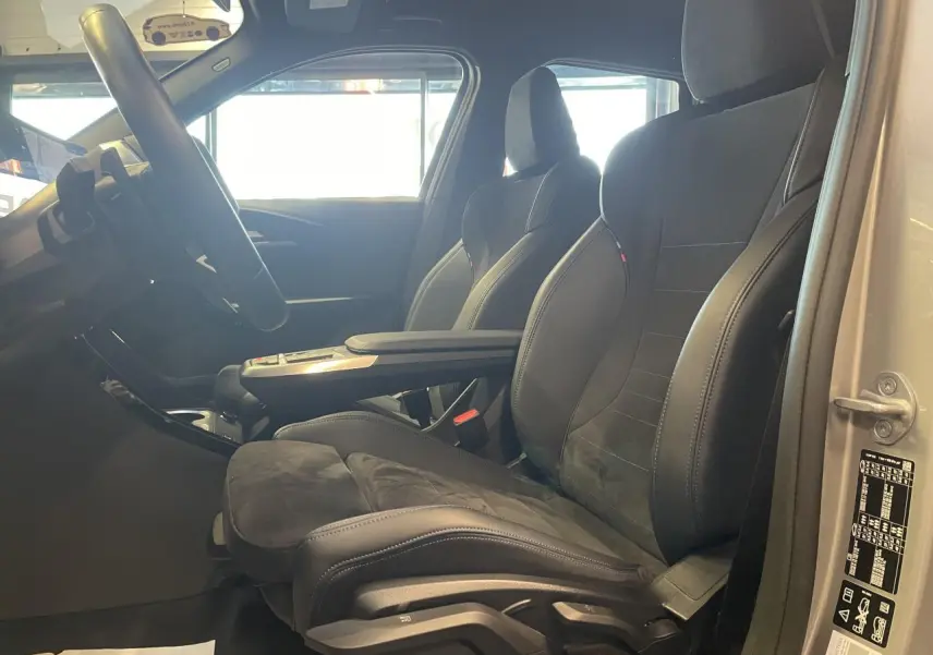 Vue intérieure côté gauche du BMW X1 xDrive 20d 2024 avec sièges M Sport en Alcantara noir et accoudoir central.