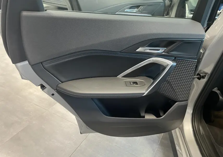 Vue rapprochée de la porte arrière gauche d’un BMW X1 xDrive 20d 2024 en Spacesilber Metallic avec garniture intérieure noire et inserts argentés.
