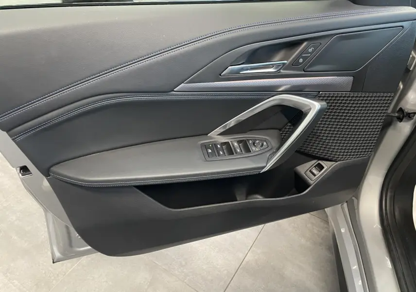 Vue intérieure côté gauche de la porte avant d’un BMW X1 xDrive 20d 2024 en Spacesilber Metallic avec finitions M Sport.