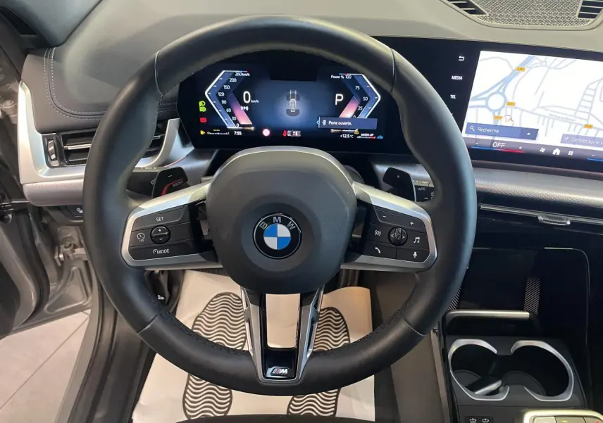 Vue intérieure centrée sur le volant M cuir noir et le combiné numérique du BMW X1 xDrive 20d 2024 en Spacesilber Metallic.