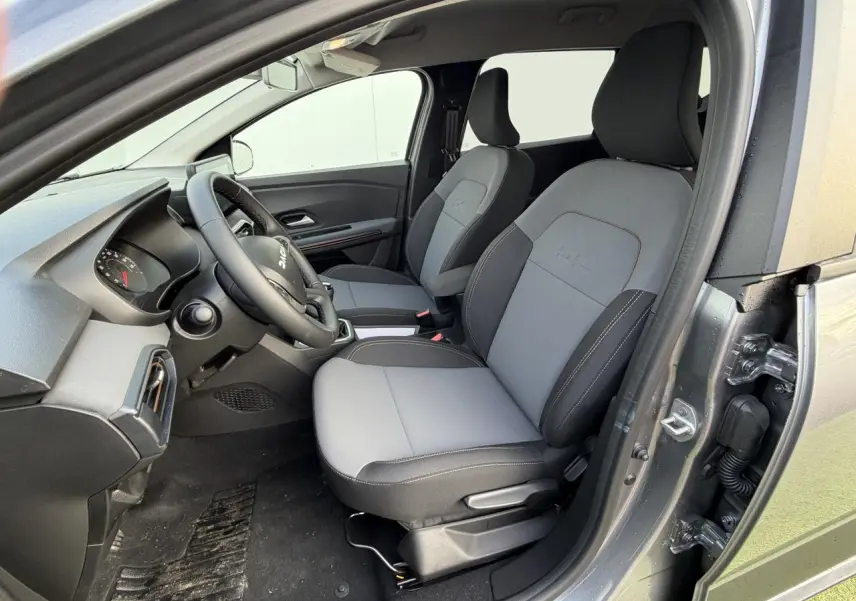Vue intérieure côté conducteur du Dacia Jogger gris schiste métal 2025, avec sièges tissu bi-ton gris et noir.