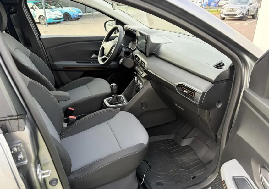 Vue intérieure côté conducteur de la Dacia Jogger gris schiste, montrant sièges et tableau de bord avec écran tactile.