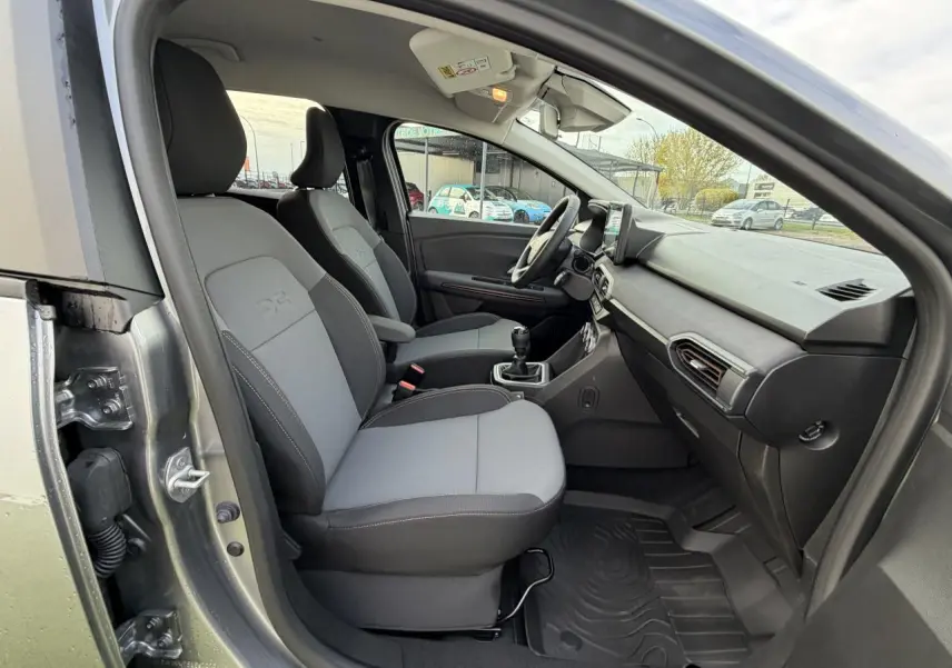 Vue intérieure côté droit du DACIA JOGGER gris shiste métal, montrant les sièges avant gris et la console centrale avec levier de vitesse manuel.