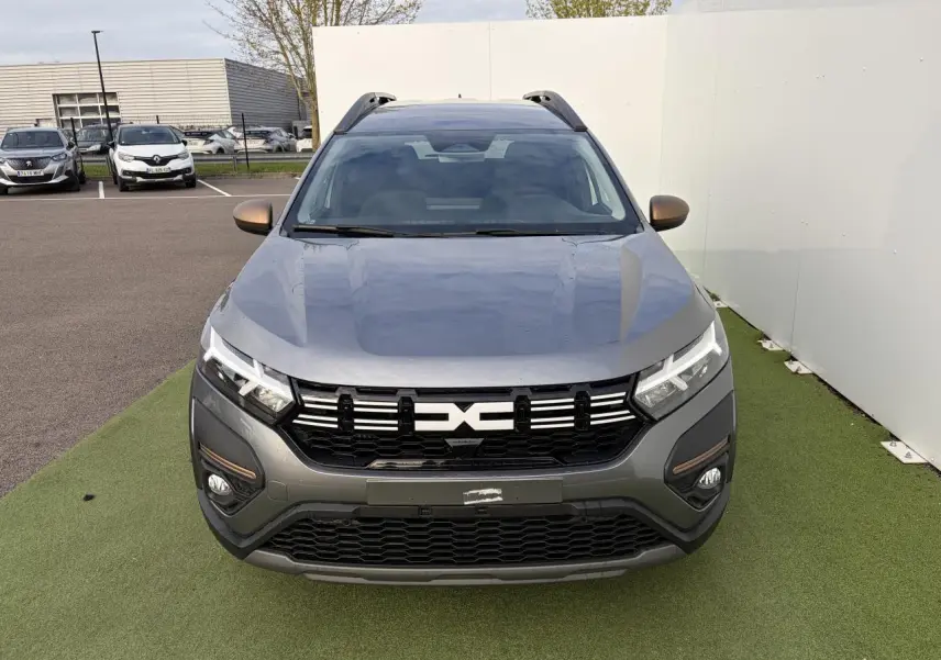 Vue de face du Dacia Jogger gris schiste métal avec calandre noire et détails brun cuivré sur les rétroviseurs et antibrouillards.