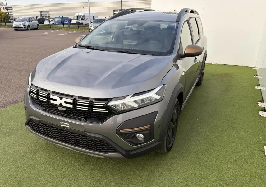 Dacia Jogger gris schiste métal vu 3/4 avant droit avec calandre noire et rétroviseurs brun cuivré.
