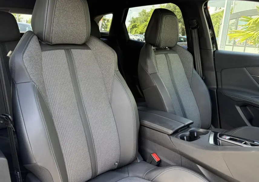 Vue intérieure sur les sièges avant gris tissu et cuir du Peugeot 3008 Plug-in Hybrid 2024 avec accoudoir central.