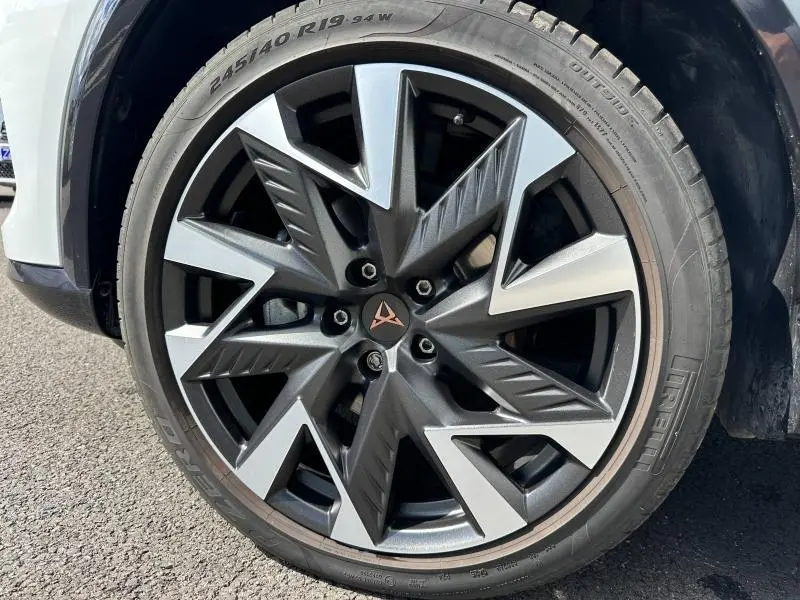 Gros plan sur la jante alu noire et argentée avec logo CUPRA, montée sur un pneu Pirelli d'un Formentor blanc Nevada.