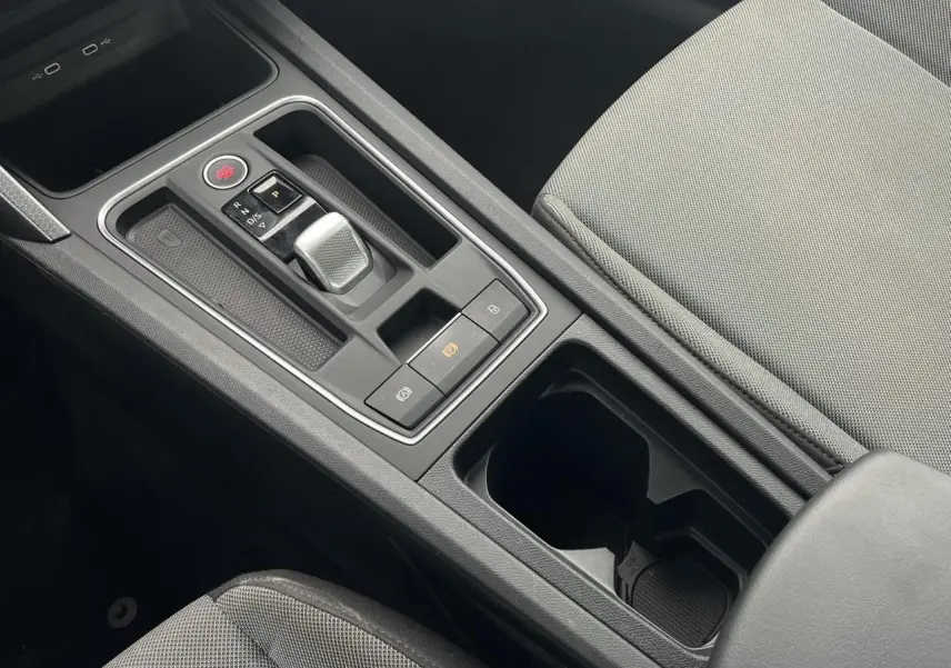 Vue rapprochée de la console centrale noire avec levier de vitesse automatique et accoudoir tissu gris clair du SEAT Leon 2024.