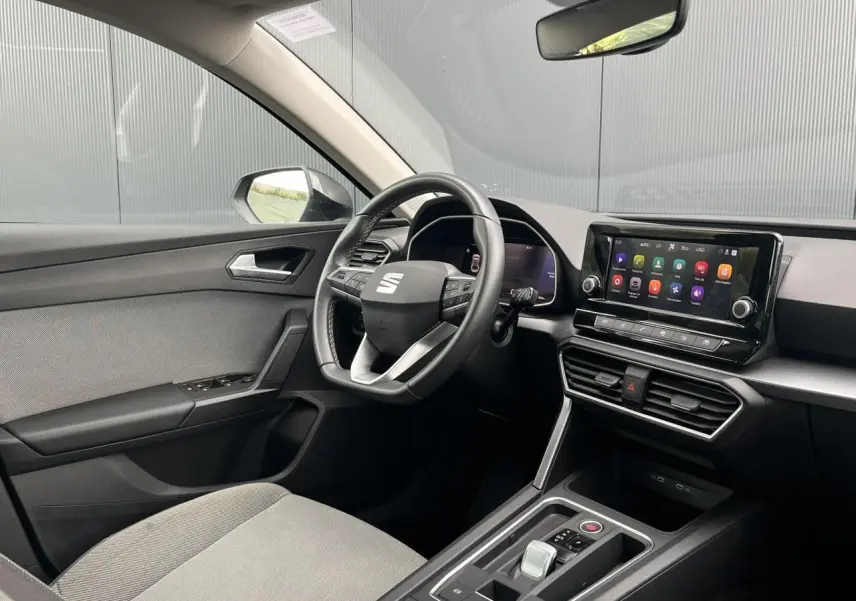 Intérieur avant droit du SEAT Leon 2024 noir Minuit, volant cuir multifonction et écran tactile central visible.