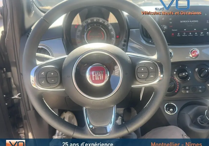 Vue rapprochée du volant et du tableau de bord de la Fiat 500 gris 2023 avec commandes intégrées au volant.