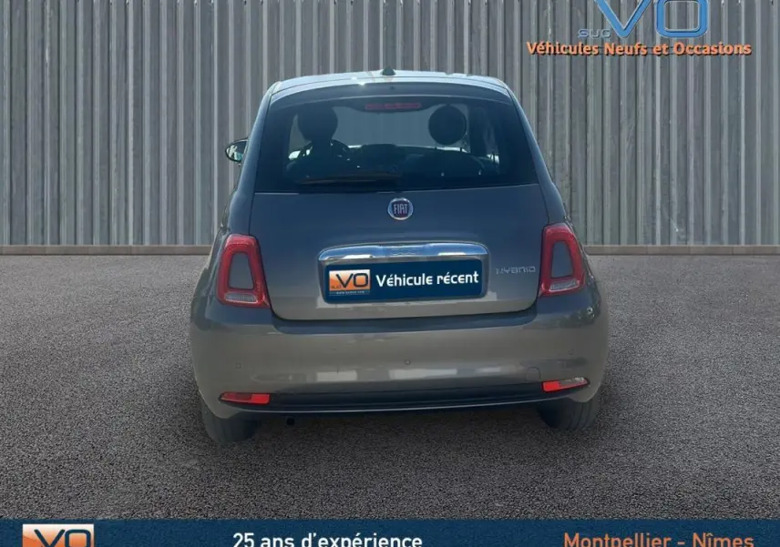 Vue arrière d'une FIAT 500 gris 2023 hybride, avec logo et plaque "Véhicule récent" visible sur un fond urbain.