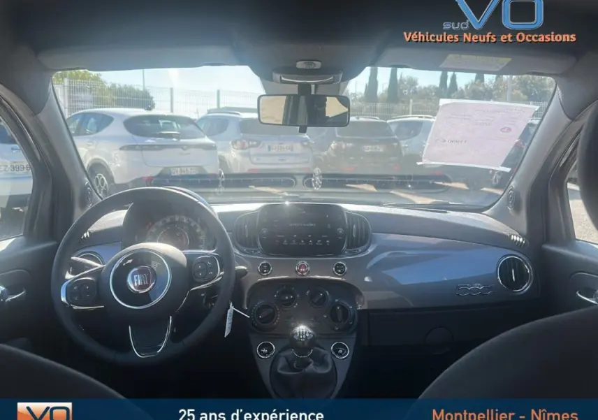 Vue intérieure avant du tableau de bord gris et volant de la Fiat 500 hybride 2023 avec boîte manuelle