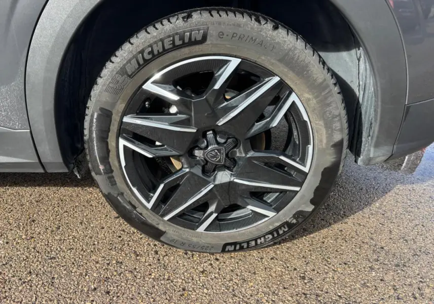 Gros plan sur la jante alliage 19 pouces noire et argentée du Peugeot 3008 Hybrid gris, avec pneu Michelin visible.