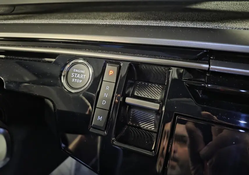 Gros plan sur la console centrale noire laquée du Peugeot 3008 2025 avec bouton start/stop et sélecteur de boîte auto.