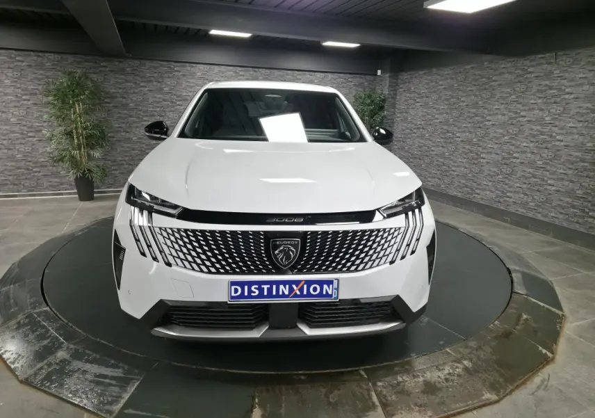 Peugeot 3008 blanc vue de face en intérieur, avec calandre noire à motif géométrique et logo lion central.