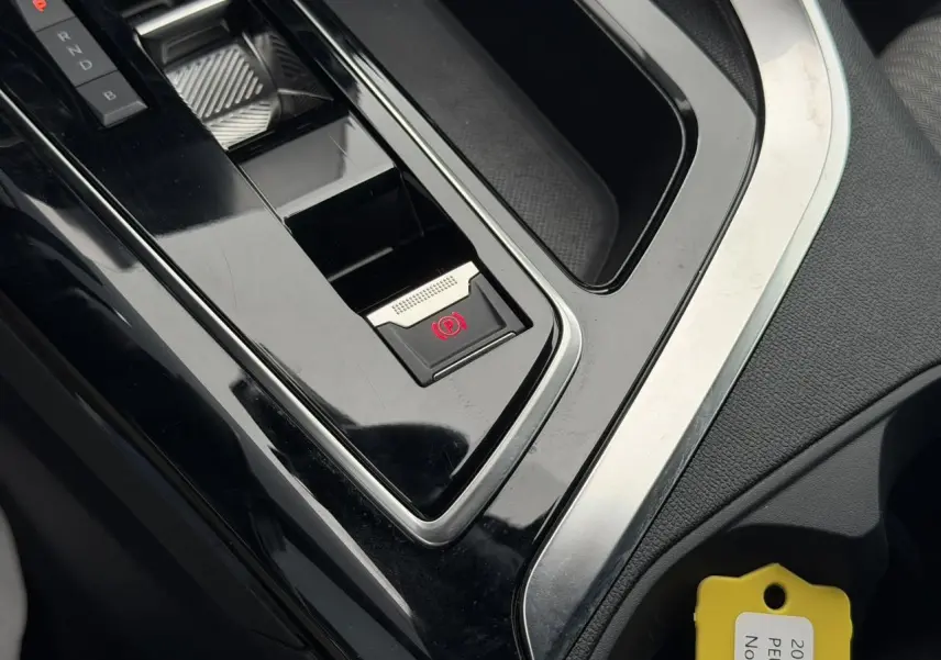 Gros plan sur la console centrale noire du Peugeot 3008 2024, avec frein de stationnement électrique et sélecteur de vitesses.