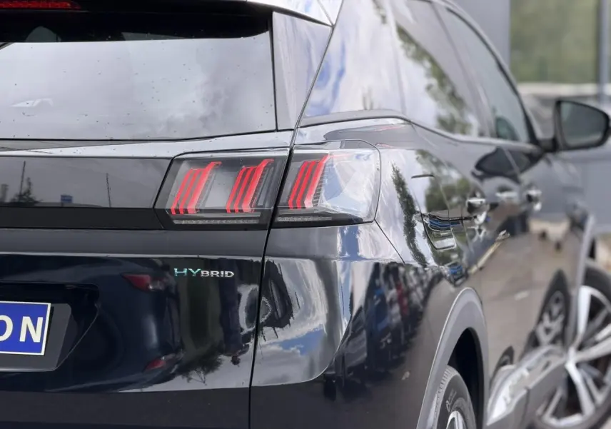 Vue 3/4 arrière droite du Peugeot 3008 Plug-in Hybrid noir Perla avec feux arrière LED et badge HYBRID visible.