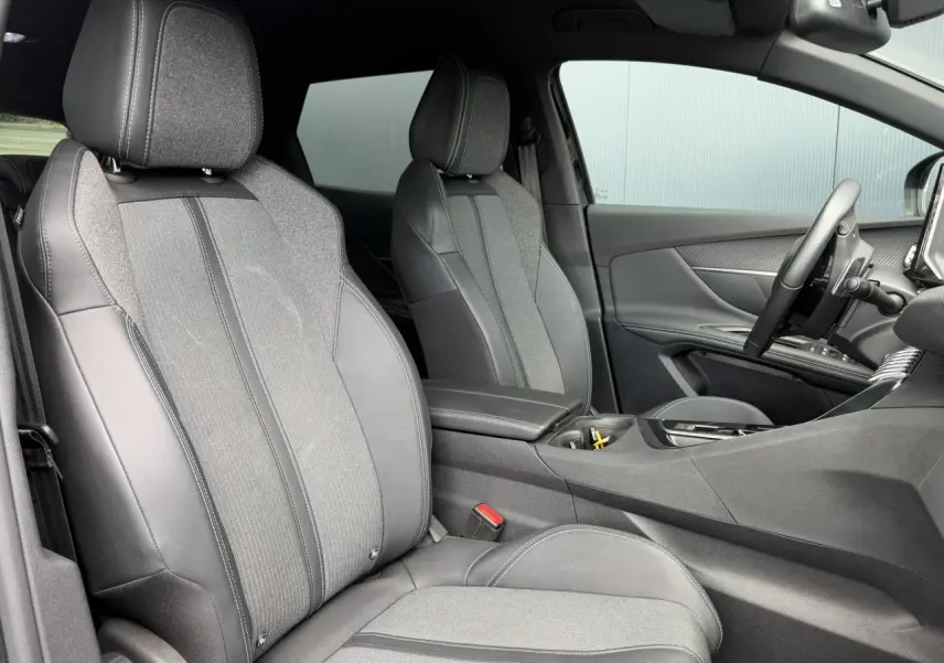 Vue intérieure côté conducteur du Peugeot 3008 2024 noir Perla, sièges tissu et cuir noir Mistral avec accoudoir central.